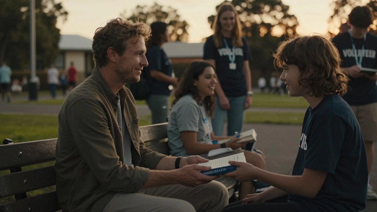 A man sharing a book with a teenager at a community center during sunset, surrounded by volunteers.