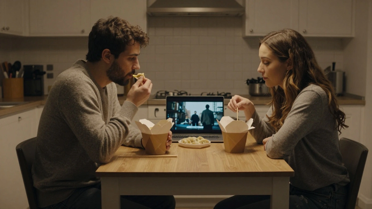 Two people sharing dumplings at a kitchen table, watching a movie quietly, radiating calm companionship.